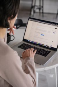 crop unrecognizable businesswoman typing on laptop at home